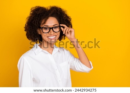 Portrait of attractive cheerful experienced wavy-haired girl assistant touching specs isolated over bright yellow color background