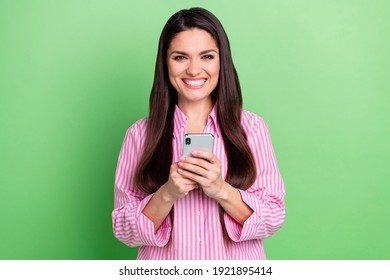 Portrait of attractive cheerful girl holding in hands using device browsing post smm app isolated over green pastel color background