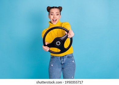 Portrait of attractive cheerful girl holding in hands steering wheel having fun isolated over bright blue color background