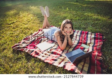 Portrait of attractive cheerful girl lying on cover using laptop spending free spare time pastime on fresh air outdoors