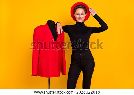 Portrait of attractive cheerful girl posing with dummy creating suit isolated over bright yellow color background