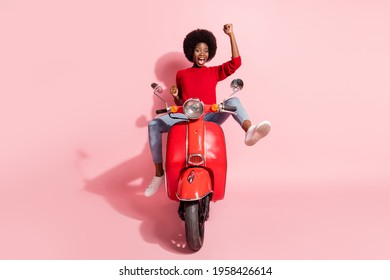 Portrait of attractive cheerful girl riding moped rejoicing having fun isolated over pink pastel color background