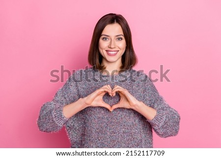 Portrait of attractive cheerful girl showing heart symbol care isolated over pink pastel color background