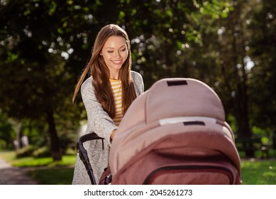 Portrait of attractive cheerful girl walking newborn carriage resting on fresh air spending free time outdoors - Powered by Shutterstock