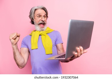 Portrait of attractive cheerful gray-haired man holding using laptop celebrating great news isolated on pink pastel color background - Shutterstock ID 1932307064