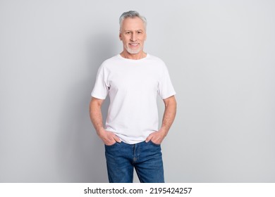 Portrait of attractive cheerful grey haired man holding hands in pockets isolated over grey pastel color background - Powered by Shutterstock