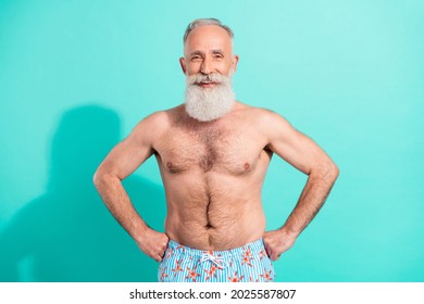 Portrait of attractive cheerful grey-haired bearded man swimmer hands on hips isolated over bright teal turquoise color background