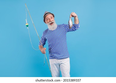 Portrait of attractive cheerful grey-haired man holding rod fresh fish food carp isolated over bright blue color background - Powered by Shutterstock