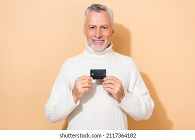 Portrait Of Attractive Cheerful Grey-haired Man Holding In Hands Black Bank Card Isolated Over Beige Pastel Color Background