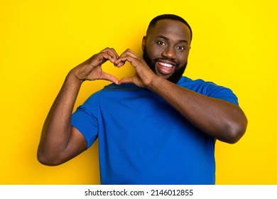 Portrait of attractive cheerful guy showing heart sign amour romance 14 February isolated over vivid yellow color background