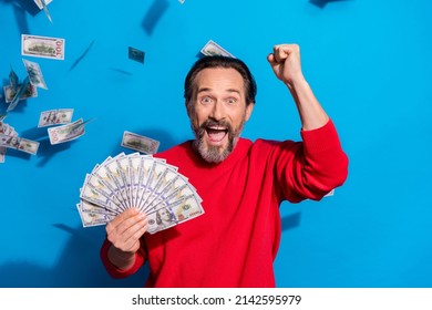 Portrait of attractive cheerful man holding cash flying credit loan rejoicing isolated over bright blue color background - Shutterstock ID 2142595979