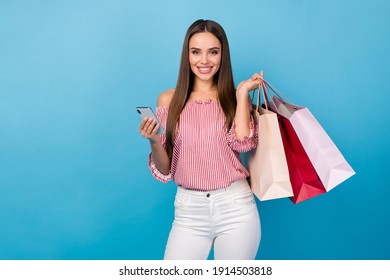 Portrait of attractive cheerful straight-haired girl using device carrying new things isolated over bright blue color background