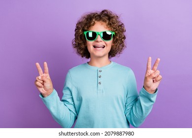 Portrait of attractive cheerful wavy-haired boy showing v-sign wearing sun specs isolated over bright violet purple color background - Powered by Shutterstock