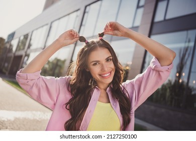 Portrait Of Attractive Cheerful Wavy-haired Girl Having Fun Fixing Top Knot Hair Bun Good Mood Rest On Fresh Air Outdoors