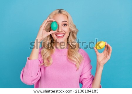 Portrait of attractive cheerful wavy-haired girl holding eggs having fun isolated over bright blue color background