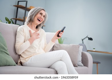 Portrait of attractive cheerful woman sitting on divan watching tv laughing resting spare time at home house apartment flat indoor