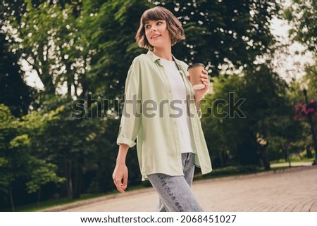 Portrait of attractive cheery dreamy girl drinking hot latte beverage resting strolling pastime on fresh air outdoors