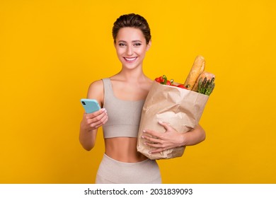 Portrait of attractive cheery girl using device buying ordering eco healthy nutrition isolated over bright yellow color background