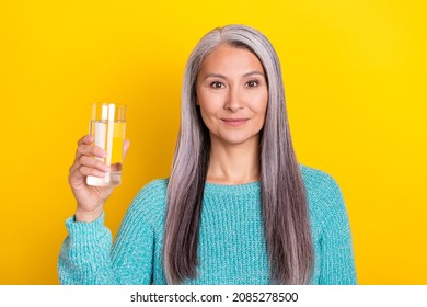 Portrait of attractive cheery grey-haired woman holding in hand fresh water isolated over bright yellow color background