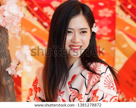 Portrait of attractive Chinese woman wearing traditional Japanese Kimono, smiling at camera, oriental beauty.