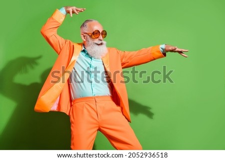 Portrait of attractive comic cheerful grey-haired man dancing having fun fooling isolated over bright green color background
