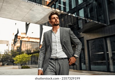 Portrait of attractive confident modern serious stylish man wearing white shirt and gray suit walking outside in business center before work and looking away. - Powered by Shutterstock