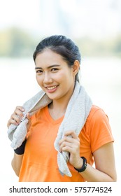 Portrait Of Attractive Confident Smile Young Asian Woman Runner With Orange Shirt Sport Watch Holding Grey Towel On White Background Outdoor For Sport Running Jogging Exercise Healthy Life Style