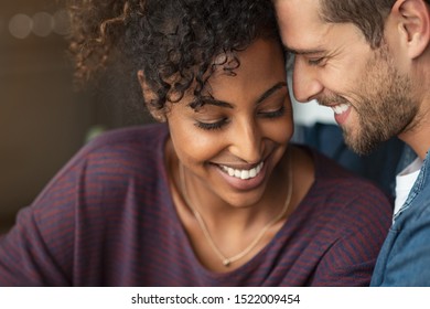 Portrait of attractive couple embracing each other. Closeup loving multiethnic couple embracing and kissing. Closeup face of cheerful boyfriend and african girl cuddling in love at home.