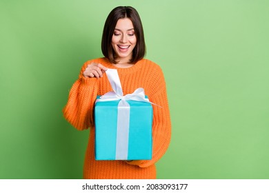 Portrait Of Attractive Curious Funny Cheerful Girl Opening Festal Giftbox Isolated Over Vibrant Green Color Background