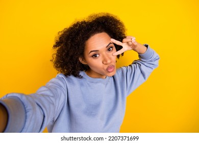 Portrait of attractive curly hairstyle girl take selfie demonstrate v-sign kiss lips isolated on yellow color background - Shutterstock ID 2207371699