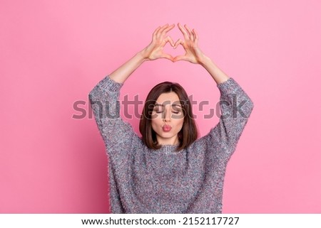 Portrait of attractive dreamy affectionate girl showing heart symbol pout lips isolated over pink pastel color background