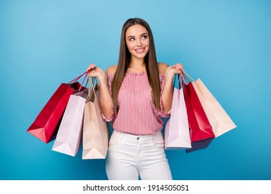 Portrait of attractive dreamy cheerful straight-haired girl holding in hand carrying new things isolated on bright blue color background