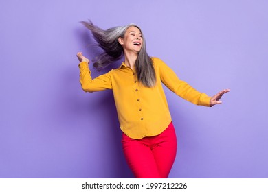 Portrait of attractive dreamy cheerful woman dancing enjoying throwing hair isolated over bright violet purple color background