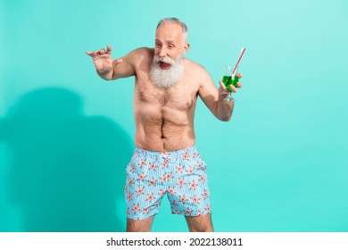 Portrait of attractive elderly cheery funky grey-haired man drinking mojito having fun isolated over bright teal turquoise color background