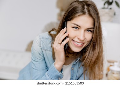 Portrait of attractive female freelancer or student sitting at the chair, looking at camera and using laptop. Beautiful business woman talking with coworker by the phone, smiling, discussing project. - Powered by Shutterstock