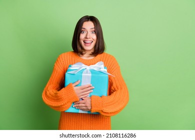 Portrait of attractive funny cheerful amazed girl hugging festal giftbox isolated over bright green color background