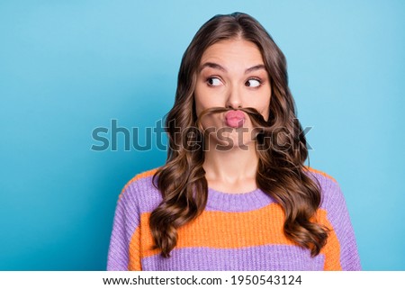 Portrait of attractive funny girl grimacing making fake mustache looking aside copy space isolated over bright blue color background