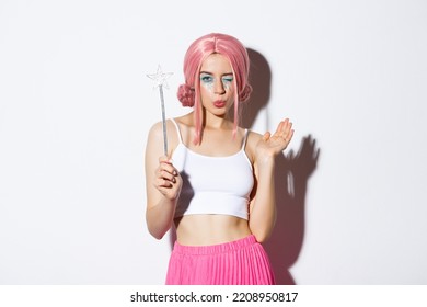Portrait Of Attractive Girl Cosplay Fairy For Halloween, Wearing Pink Wig And Holding Magic Wand, Standing Over White Background