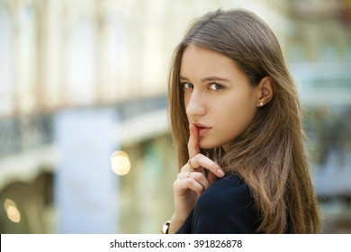 Portrait of attractive girl with finger on lips, concept of student show quiet, silence, secret gesture, young pretty brunette woman, indoor