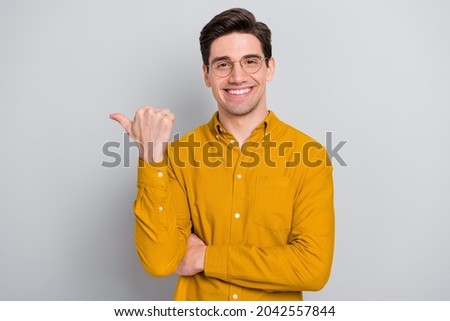 Portrait of attractive glad cheerful man manager demonstrating ad copy space isolated over grey color background
