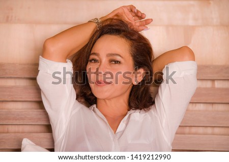 portrait of attractive happy and beautiful mature woman aged 50s to 60s smiling cheerful and charming at home bedroom sitting on bed in the morning in successful middle aged lady concept