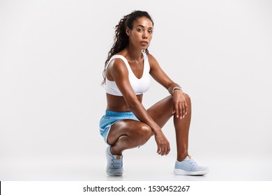 Portrait of an attractive healthy fit confident african sportswoman sitting while resting after workout isolated over white background - Powered by Shutterstock