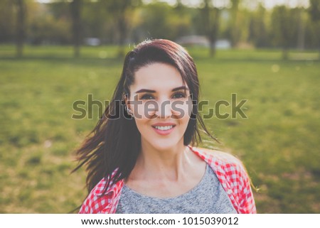 portrait of attractive hipster girl smiling outdoors. concept of freedom purposeful teenager. woman dressed in a gray T-shirt and a red shirt in a cage