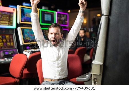 Portrait of an attractive Hispanic man looking very excited about winning some money playing slots in a casino