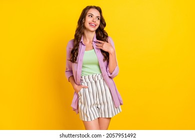 Portrait of attractive impressed cheerful wavy-haired girl good mood isolated over bright yellow color background