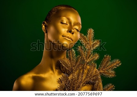 Portrait of attractive lady closed eyes x-mas pine branch bodyart covered glowing metal isolated on green background