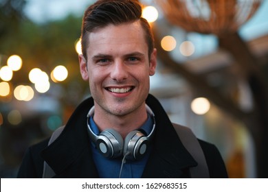 Portrait attractive man smiling confident male in city evening with lights in background