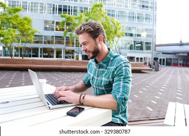 Portrait Of An Attractive Man Smiling With Laptop Outside