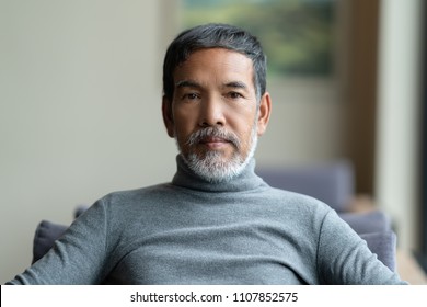 Portrait Of Attractive Mature Asian Man Retired With White Stylish Short Beard Sitting On Couch At Coffee Shop Cafe. Close Up Of Old Handsome Businessman Or Entrepreneur In Urban Lifestyle Concept.