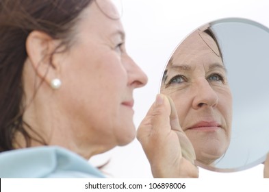 Portrait Of An Attractive Middle Aged Woman Looking Into A Mirror, With Focus Set On The Mirror Image.